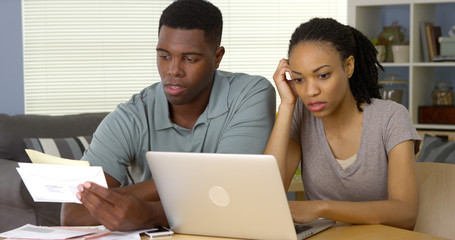 Frustrated young Black couple going over bills and finances online