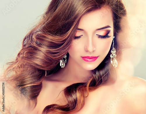 Naklejka ścienna Beautiful model brunette with long curled hair and jewelry earrings