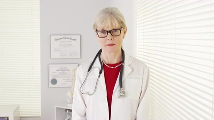 Wall Mural - Serious senior woman doctor looking at camera