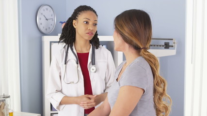 Wall Mural - African American doctor talking to female Asian patient in exam room