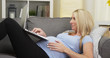 © rocketclips - Happy pregnant woman lying on couch using laptop