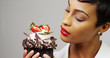© Mark Adams - Black woman admiring a fancy dessert cupcake with chocolate and strawberries