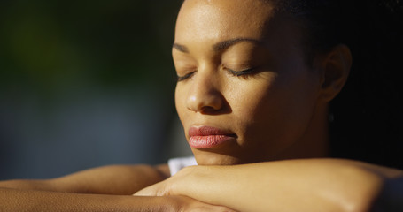 Wall Mural - Black woman sitting with eyes closed outdoors