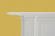 simplistic white fireplace mantle against yelllow wall