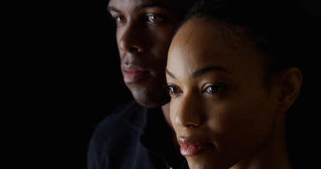 Dramatic rack focus between African American man and woman on black background