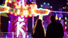 Couple Watching People On Amusement Ride At Night