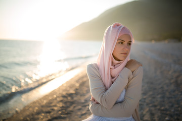 Wall Mural - Muslim woman on the beach spiritual portrait.Humble muslim woman praying on the beach.Summer holiday,muslim woman walking on the beach