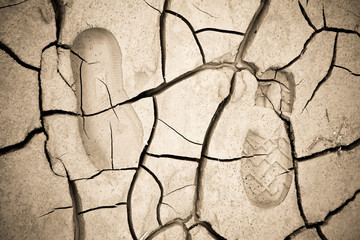 Heavy footprint left on a muddy sand by a male boot.