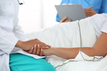 Wall Mural - Friendly female doctor's hands holding patient's hand