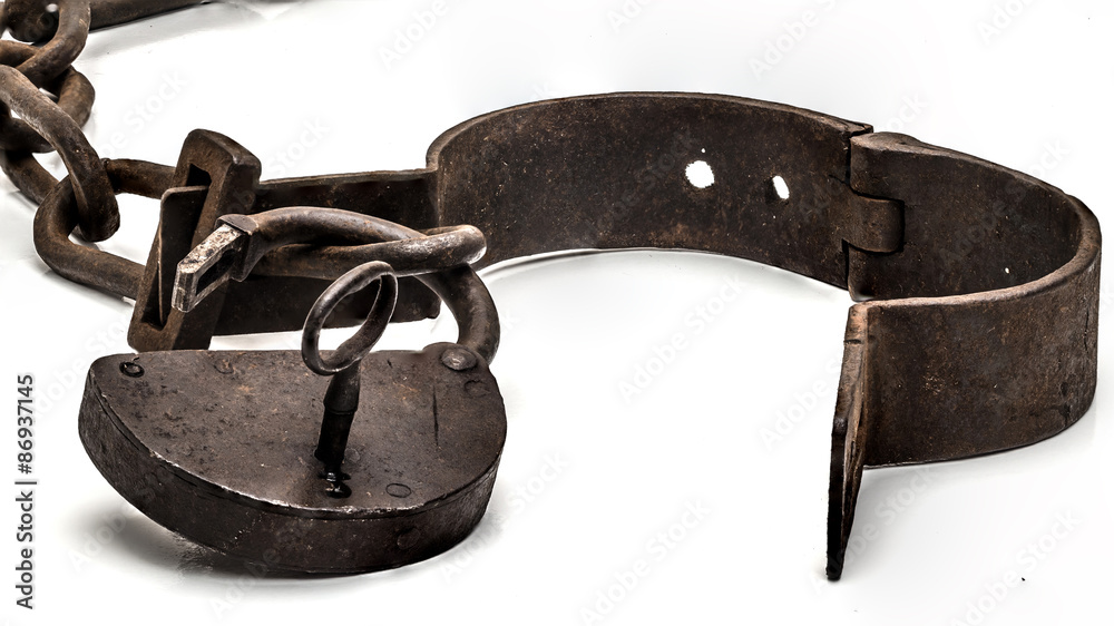 Rusty old shackles with padlock, key and open handcuff used for locking up prisoners or slaves between 1600 and 1800. - obrazy, fototapety, plakaty 