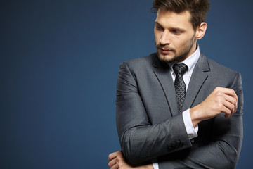 Handsome young business man standing on blue background