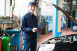 Mechanic holding a clipboard in front of a car