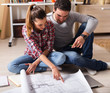 © BalanceFormCreative - Young couple examining blueprints of they new house.