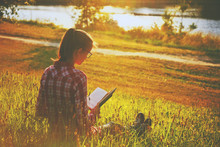 Girl Reading Book On Summer Shore Of River