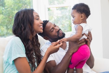 Wall Mural - Happy couple with their baby girl on couch