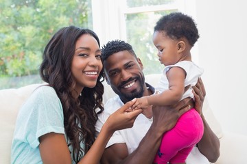 Wall Mural - Happy couple with their baby girl on couch