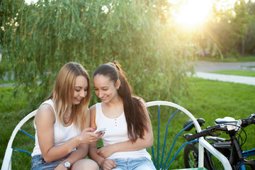 Wall Mural - Cheerful teenage girls with cellphone in park