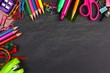 © Jenifoto - School supplies top corner border on a chalkboard background