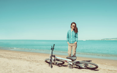 Wall Mural - Woman with a bicycle standing on beach