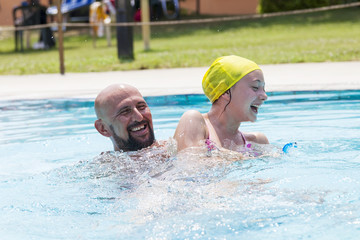 hipster father playing with her daughter in the pool