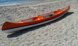 orange plastic sea kayak on beach with no one	