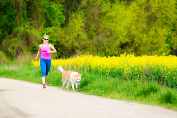 Wall Mural - Woman running in summer park with dog