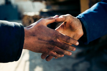 Handshake two workers men at industry close up.