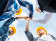 © Syda Productions - close up of builders in hardhats making high five