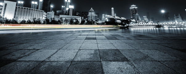 Wall Mural - light trails and cityscape with empty road floor