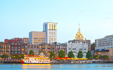 savannah georgia usa, skyline of historic downtown at sunset with illuminated buildings and steam bo