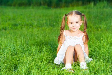 happy child little girl in  white dress lying on grass Summer