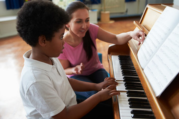 male student enjoying piano lesson with teacher