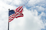 Fototapeta Miasta - US American flag waving in the wind with beautiful blue cloudy sky in background