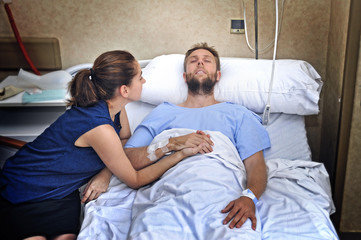 couple at hospital room man in bed and woman holding hand caring