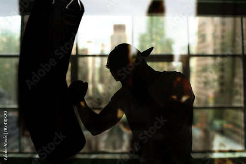 Fotografia Boxer hits a punching bag against the window, training