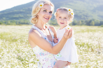 Wall Mural - Happy family mother and daughter in field of daisy flowers