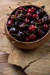 Wall Mural - Wooden bowl with sweet organic cherries, close-up, studio shot