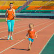 © ruslimonchyk - Mother & little daughter running around the stadium. Child runs away from mom at the stadium.