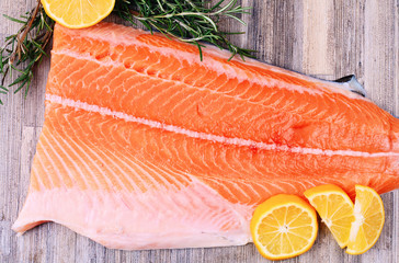 Raw salmon fillet with lemon and herbs on wooden background