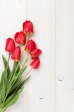 Fototapeta Tulipany - Red tulips bouquet over wood