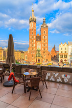 Table On Restaurant Terrace With View Of Mariacki Cathedral On Main Market Square Of Krakow City, Poland