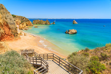Wooden Walkway To Famous Praia Dona Ana Beach With Turquoise Sea Water And Cliffs, Portugal