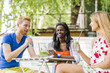 © NDABCREATIVITY - Young and happy friends sitting talking at a table