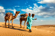 Cameleer camel driver with camels in dunes of Thar desert