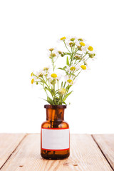 Alternative medicine concept - bottle with camomile on wooden ta