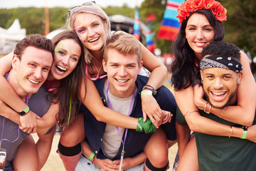 Friends giving piggy backs at a music festival