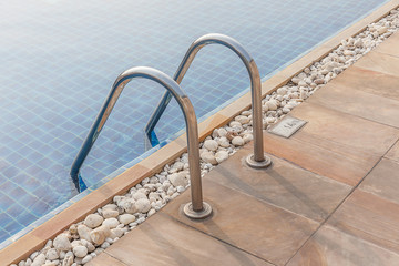 Steel ladder and clear blue swimming pool.