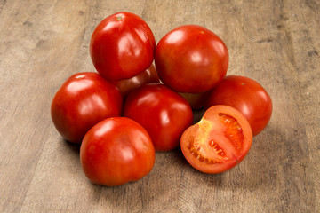 Some tomatoes over a wooden surface on a tomato field as backgro