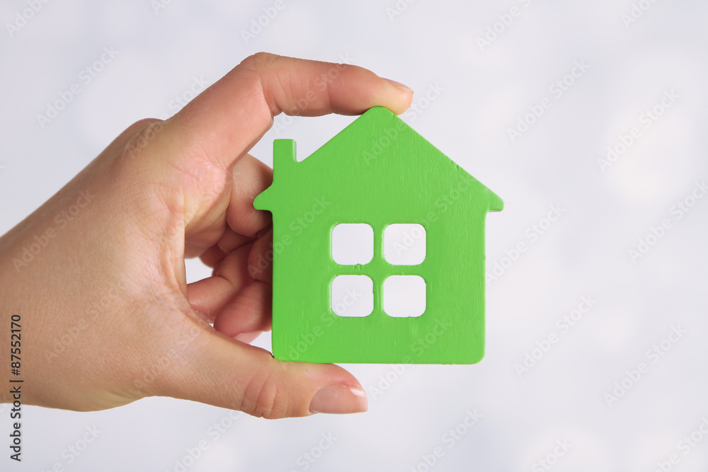 Female hand with model of house on blurred background