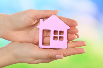 Canvas Print - Female hands holding model of house on bright background